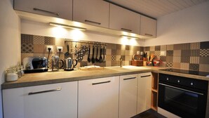 A modern kitchen with white cabinets, a black oven, and a patterned backsplash. - Apartment 'Appartement Deux Chambres' with Mountain View, Private Terrace and Wi-Fi (Briançon)