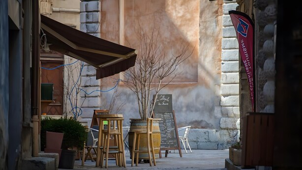 An outdoor seating area with tables and chairs, a chalkboard menu, and a flag.