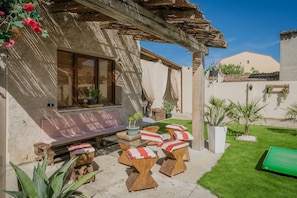 Un patio con una mesa y sillas de madera, un banco y un tapete verde.