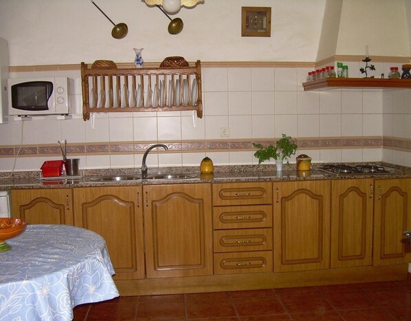 Una cocina con armarios de madera, un lavamanos, un microondas, un reloj y una estufa.