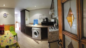 A compact kitchen with a washing machine, a microwave, and a gas stove.
