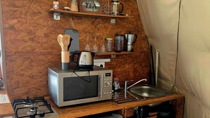 A compact kitchen with a microwave, kettle, and small refrigerator.