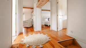 A hallway with wooden flooring, white walls, and a white rug with tassels. - Maison "Opaline" with Shared Pool & Spa, Private Terrace, and Wi-Fi (Vergné)