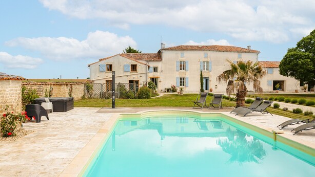 A swimming pool with lounge chairs, a patio area, and a large building with multiple windows and a tiled roof. - Maison "Opaline" with Shared Pool & Spa, Private Terrace, and Wi-Fi (Vergné)