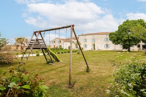 A grassy area with a swing set, a ladder, and a building with a tiled roof in the background. - Maison "Opaline" with Shared Pool & Spa, Private Terrace, and Wi-Fi (Vergné)