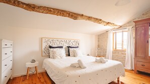 A bedroom with a wooden ceiling, a bed with white bedding and pillows, a bedside table with a lamp, and a wardrobe. - Maison "Opaline" with Shared Pool & Spa, Private Terrace, and Wi-Fi (Vergné)