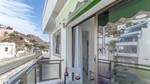 A balcony with a table, two wine glasses, a bottle of wine, and a plate of chips.