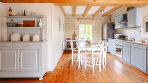 A kitchen with white cabinets, a wooden ceiling, and a stone wall. - Maison 'Ambre' with Shared Pool & Spa, Private Terrace, and Wi-Fi (Vergné)