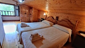 Una camera in legno con due letti, un comodino, una lampada e una finestra vista alberi.