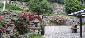 A stone wall with climbing roses, a stone bench, and a rustic outdoor seating area. - 'Rural Rubó' Apartment with Mountain Views, Private Terrace, and Wi-Fi (Alles)