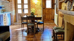 A rustic kitchen with a wooden table, chairs, and a brick wall. - ‘La Tablá’ Rural Apartment with Mountain Views, Private Terrace, and Wi-Fi (Alles)