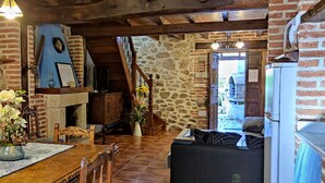 A rustic interior with exposed brick walls, a wooden dining table, and a fireplace. - ‘La Tablá’ Rural Apartment with Mountain Views, Private Terrace, and Wi-Fi (Alles)