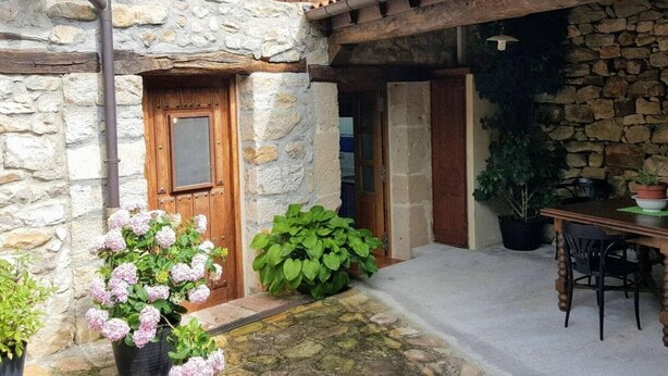 A stone building with a wooden door, a balcony, and potted plants. - ‘La Tablá’ Rural Apartment with Mountain Views, Private Terrace, and Wi-Fi (Alles)