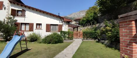 A residential building with a garden, a blue slide, and a stone pathway.