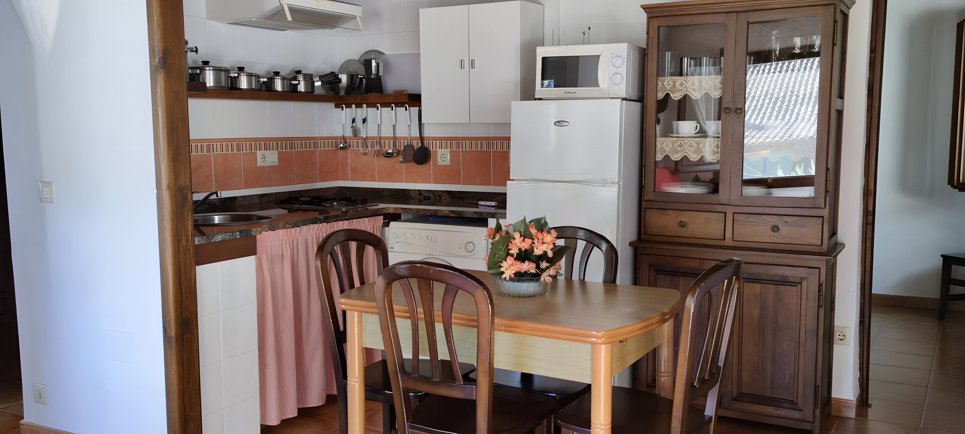 Une cuisine équipée d’un four à micro-ondes, d’une cuisinière, de placards et d’une table à manger avec des chaises.