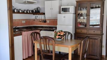 Une cuisine équipée d’un four à micro-ondes, d’une cuisinière, de placards et d’une table à manger avec des chaises.