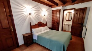 A bedroom with a wooden bed, nightstands, a wooden wardrobe, and a bathroom with a sink and mirror. - Apartment 'Jana' with Mountain View, Private Terrace and Wi-Fi (Alles)