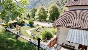 A residential area with a garden, a swing set, and a house with a tiled roof. - Apartment 'Jana' with Mountain View, Private Terrace and Wi-Fi (Alles)