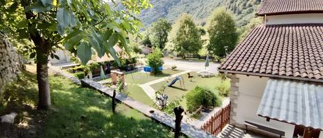 A residential area with a garden, a swing set, and a house with a tiled roof.