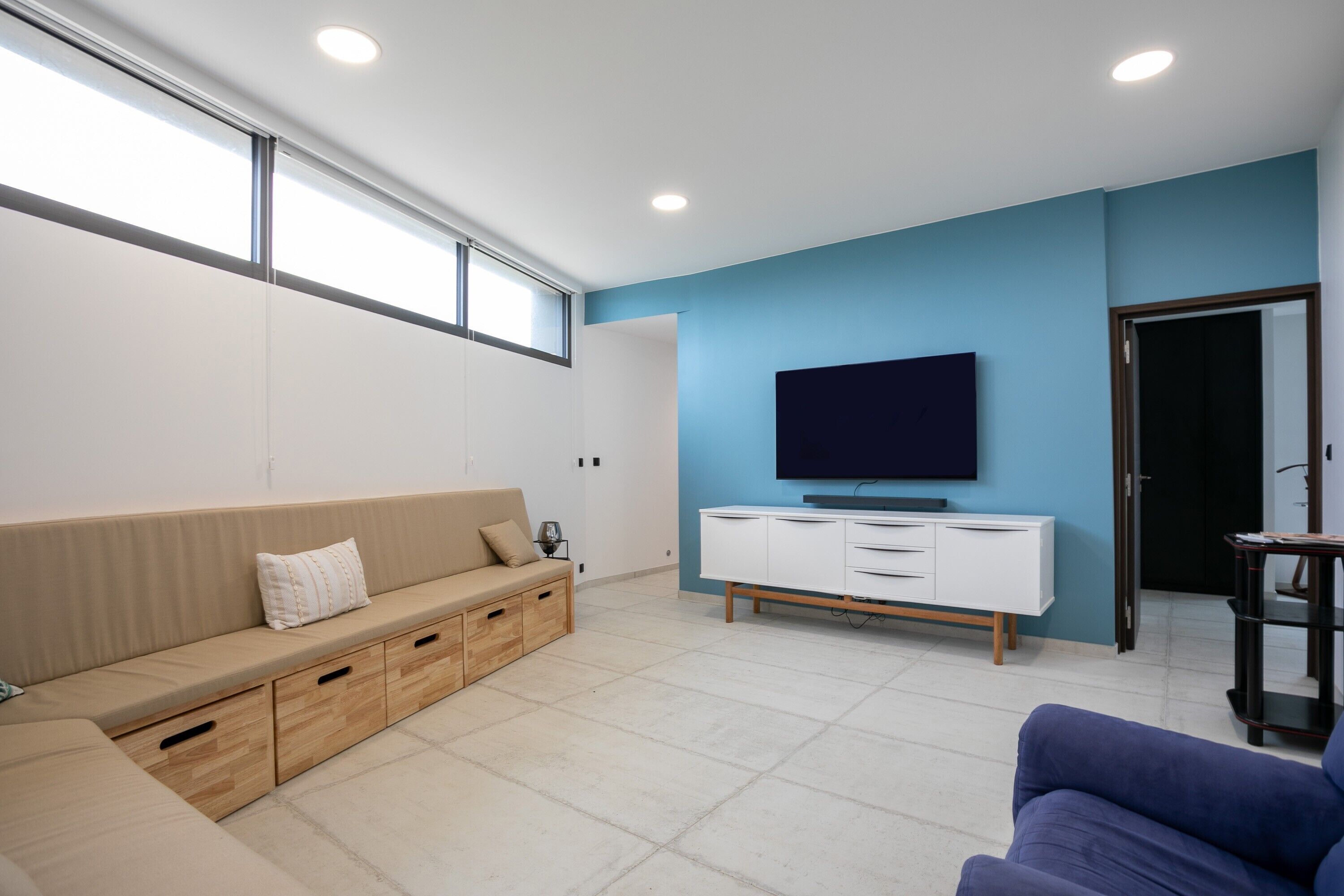 Una sala de estar moderna con sofá, televisor y unidad de almacenamiento.