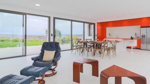 A modern interior with a dining area, a kitchen, and a seating area with a view. - Villa 'Ker Marie' with Sea View, Private Terrace and Wi-Fi (Locquirec)