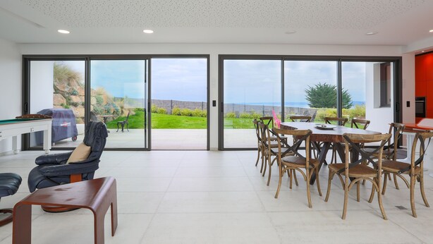 A spacious room with a dining area, a massage chair, and a view of the outdoors. - Villa 'Ker Marie' with Sea View, Private Terrace and Wi-Fi (Locquirec)