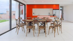 A modern kitchen with a large island, round dining table, and six chairs. - Villa 'Ker Marie' with Sea View, Private Terrace and Wi-Fi (Locquirec)
