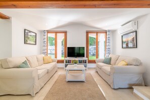 A living room with two sofas, a coffee table, a TV, and a bookshelf. - 'Can Botana 10' with Sea View, Wi-Fi and Air Conditioning (Cala Sant Vicenç)