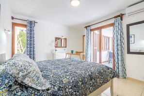 A bedroom with a bed, a desk, a chair, and a window with curtains. - 'Can Botana 10' with Sea View, Wi-Fi and Air Conditioning (Cala Sant Vicenç)