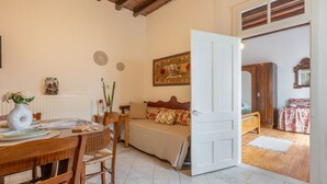 A cozy room with a wooden dining table, a sofa, a bed, and a door leading to another room.