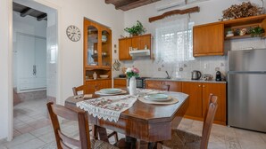 A dining area with a wooden table, chairs, and a kitchen in the background.