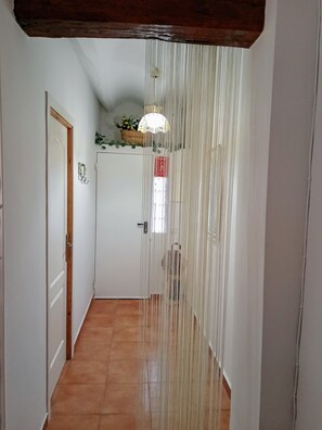 A hallway with a white door, a wooden ceiling, and a hanging light fixture. - Rural house 'Casa Rural San Antón' with mountain views (Quesa)
