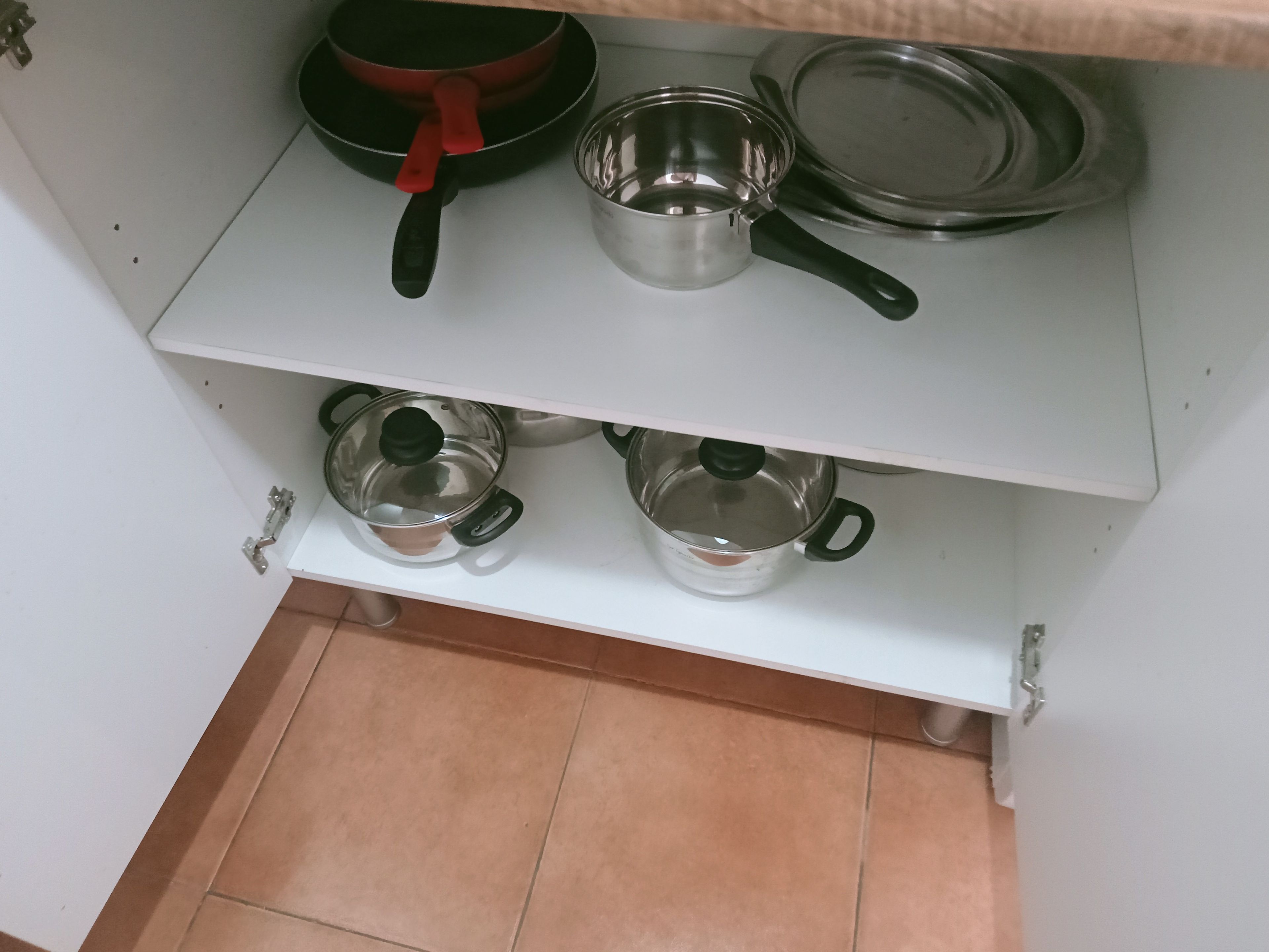 A kitchen with two shelves, each holding various cookware items.