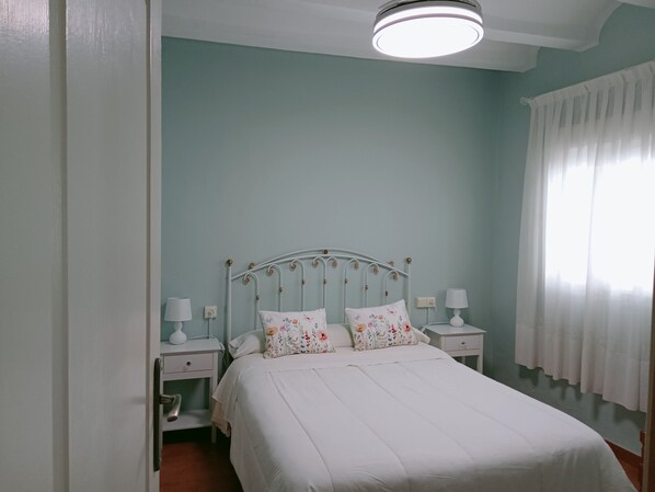 A bedroom with a bed, two bedside tables, a nightstand, a window with curtains, and a ceiling light. - Rural house 'Casa Rural San Antón' with mountain views (Quesa)