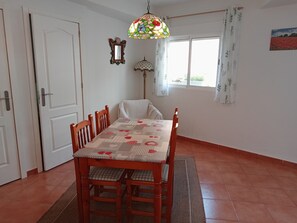 A dining area with a table set for four, a patterned tablecloth, and a decorative hanging light fixture. - Rural house 'Casa Rural San Antón' with mountain views (Quesa)