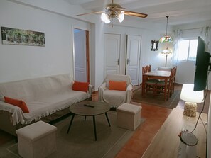A living room with a sofa, armchairs, a coffee table, and a dining table.