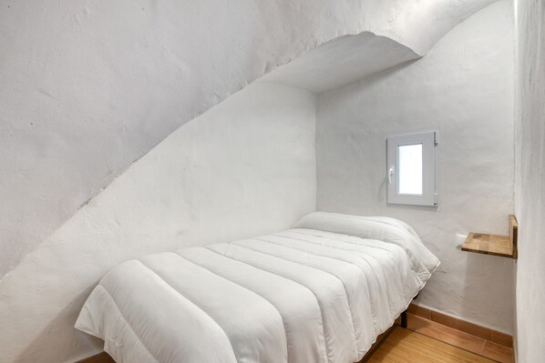 A small, white, single-bed room with a sloped ceiling and a window. - Rural house 'Casa Rural San Antón' with mountain views (Quesa)