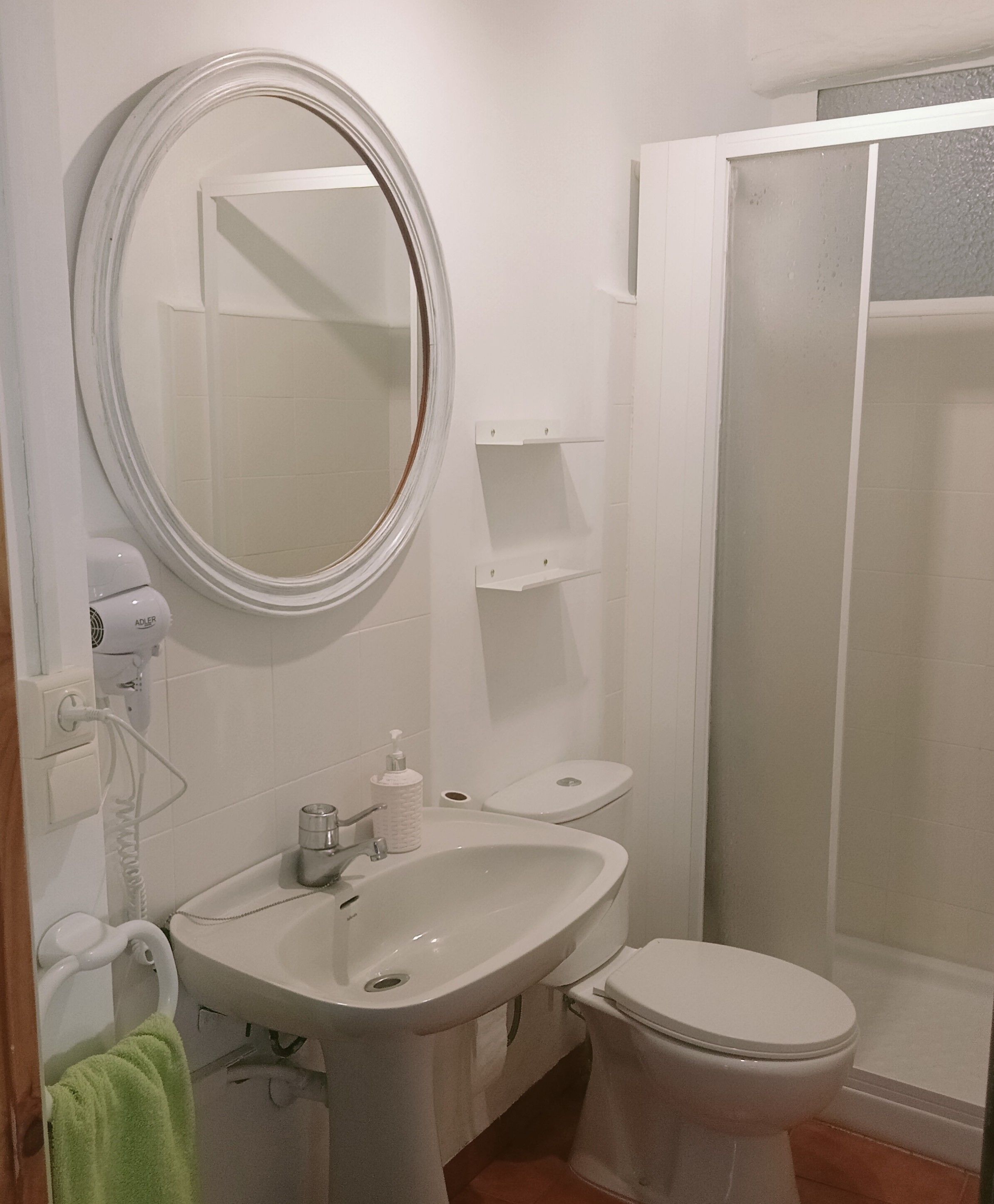 Een badkamer met een wastafel, toilet, spiegel en douchecabine.