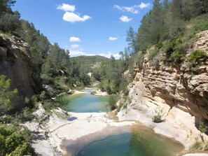 Un paysage naturel comprenant une rivière, un terrain rocheux et une forêt dense.