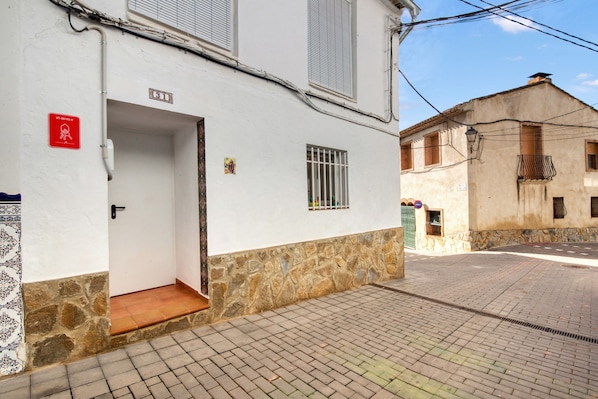 A building with a white exterior, a tiled entrance, and a stone base.