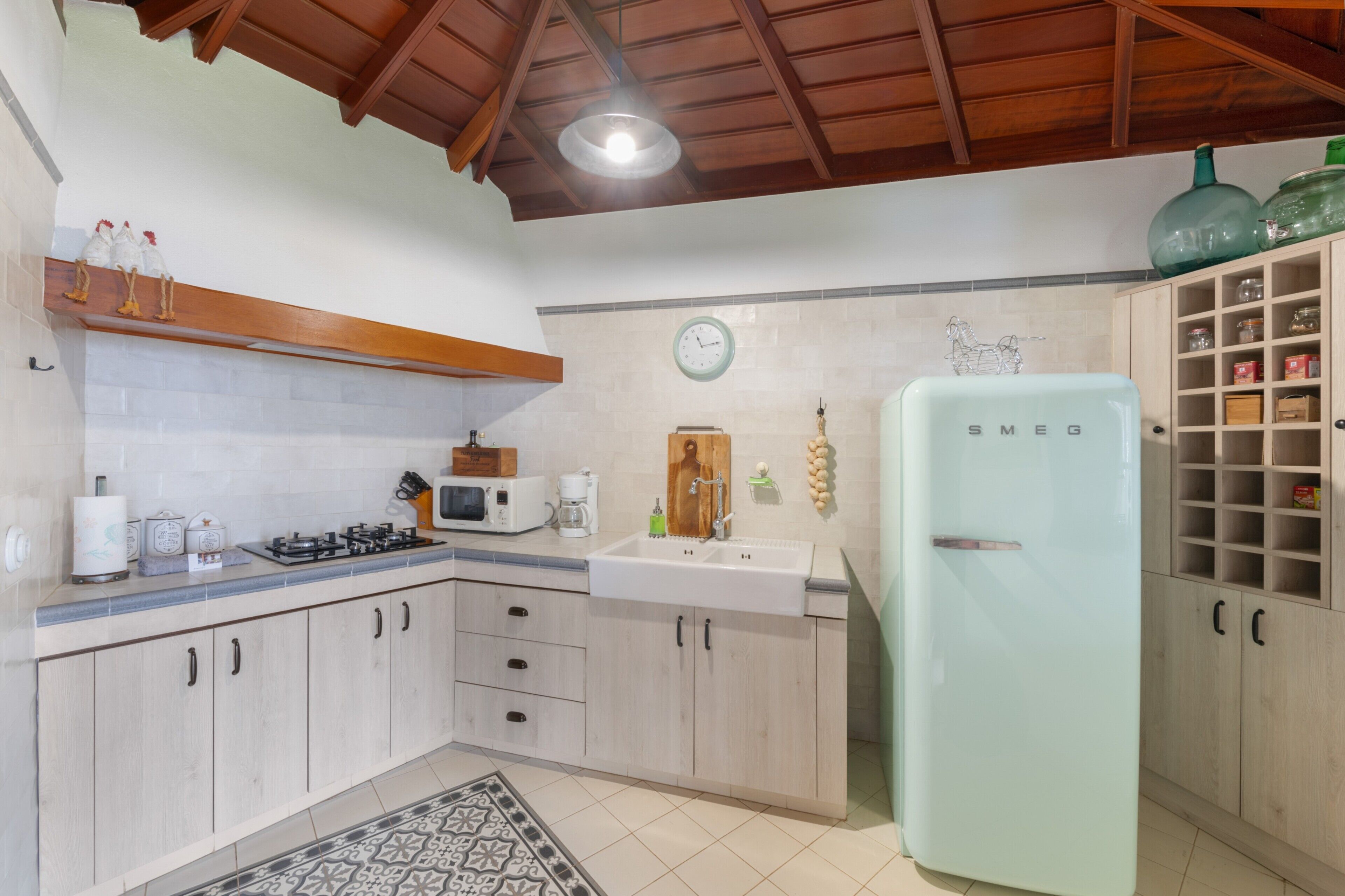 A kitchen with wooden cabinets, a white sink, a microwave, a stove, and a refrigerator.