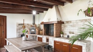 Una cocina con horno de ladrillo, mesa de madera y armarios.