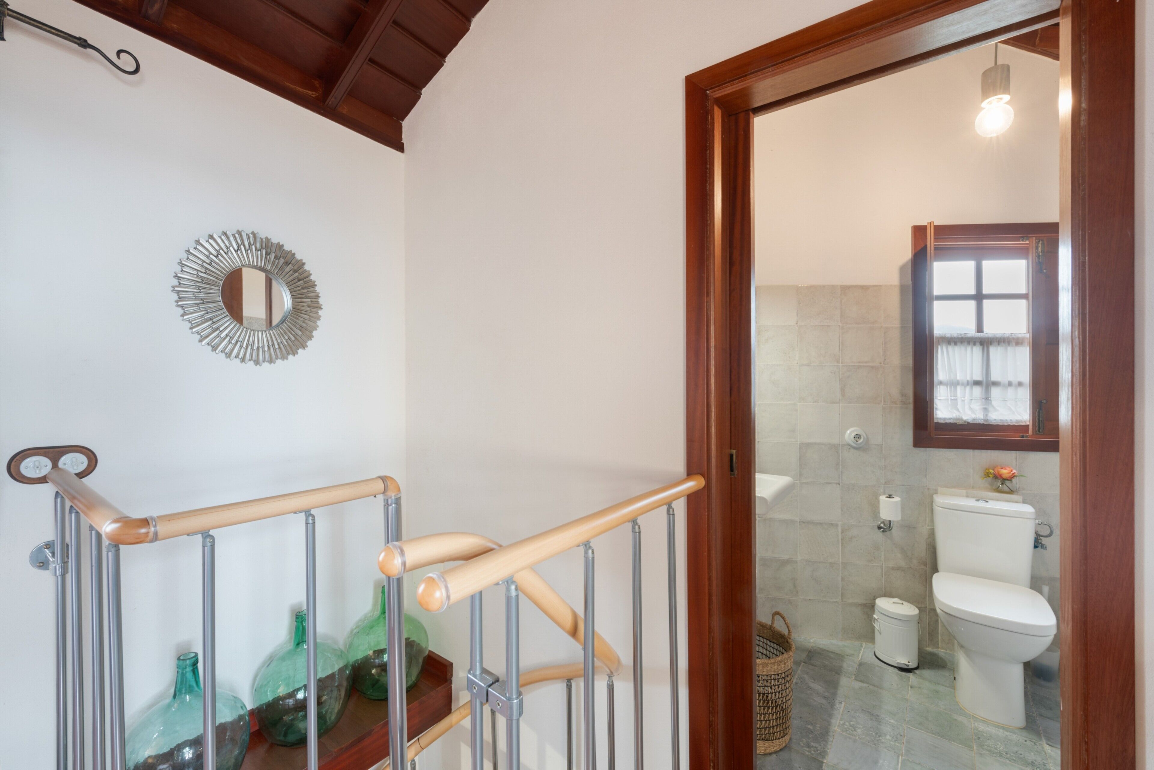 Ein Badezimmer mit Toilette, Waschbecken, Spiegel und Duschbereich.