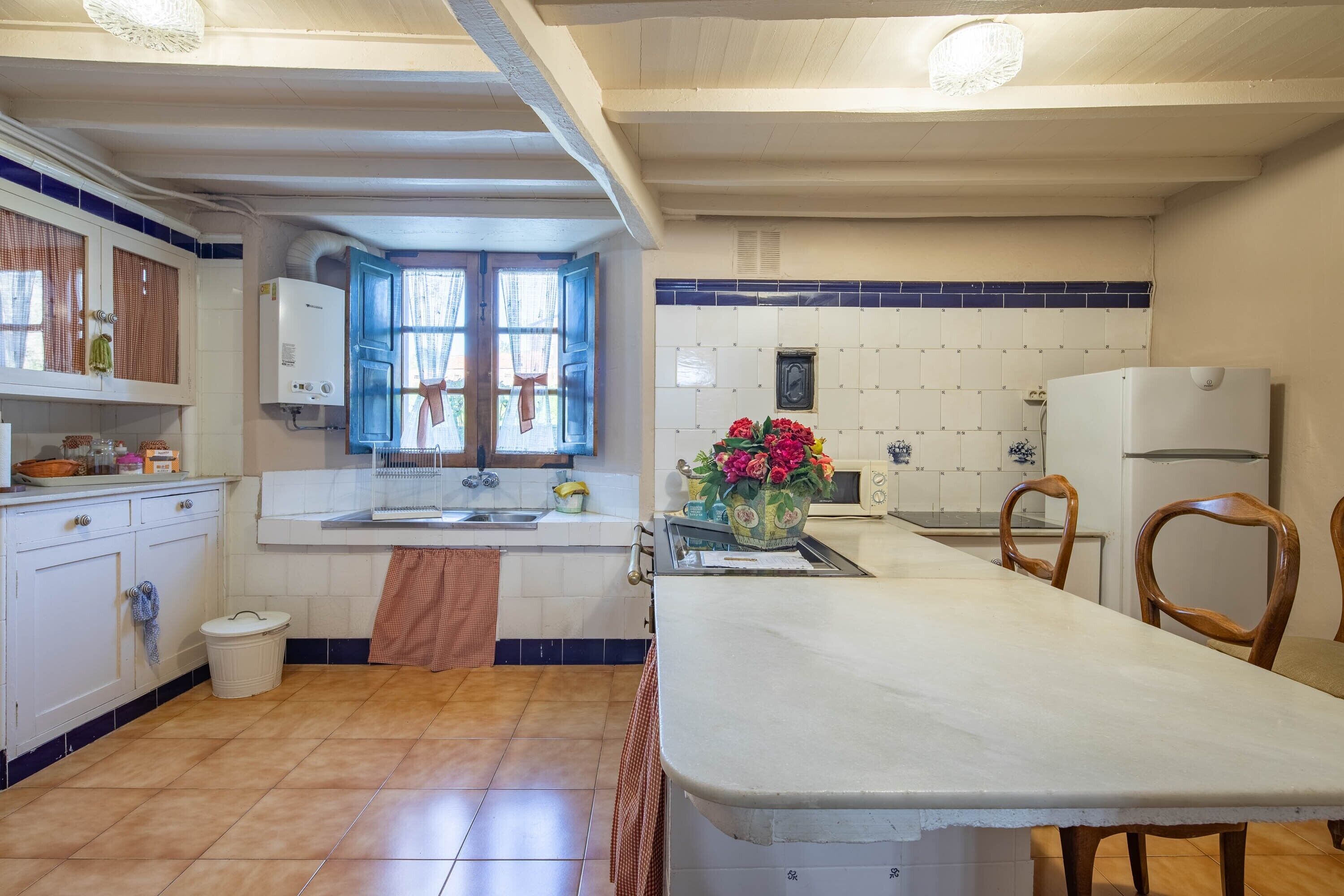 A kitchen with a central island, white cabinets, a window, and a tiled backsplash.