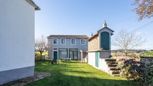A two-story house with a patio, a small garden, and a stone staircase.