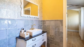 Une salle de bain avec un lavabo blanc, un miroir et un meuble-lavabo en bois.