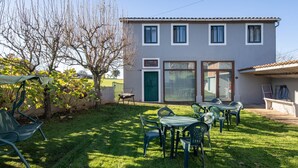 A two-story building with a patio area featuring outdoor seating and a covered table.