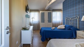 A bedroom with two beds, a dresser, a TV, and a chandelier.