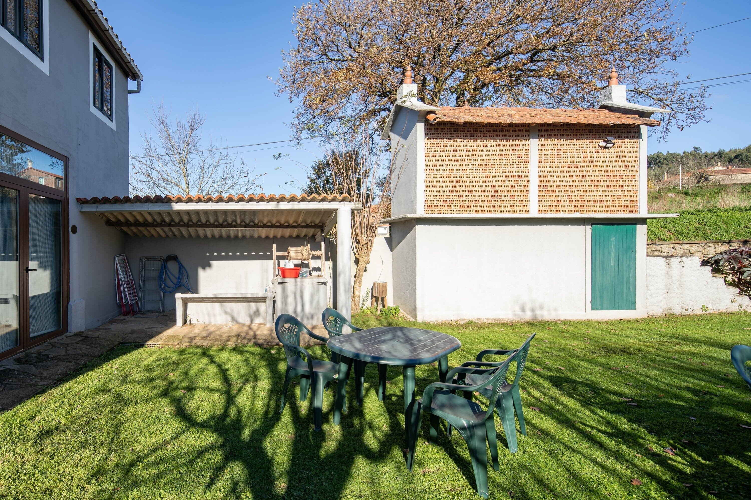 Ein Haus mit einer Terrasse, einem Tisch und Stühlen sowie einer grünen Tür.