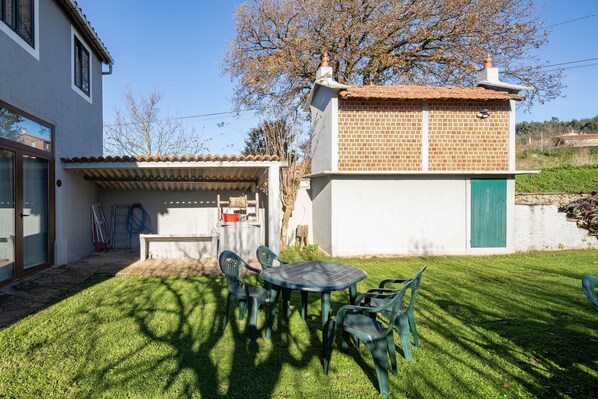 Una casa con un patio, una mesa con sillas y una puerta verde.